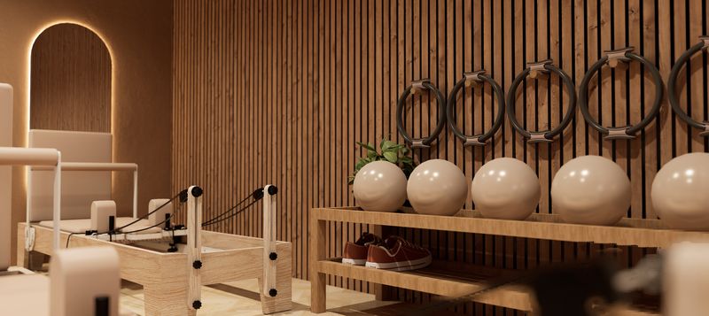 Latjeswand met pilatesringen en ballen naast een reformer